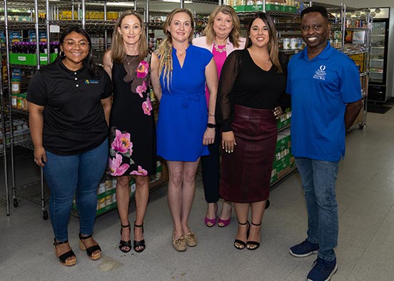 Five women and one man standing side by side while smiling