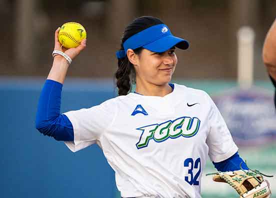 Softball player #32 in blue visor, white shirt and blue pants holding glove in left hand and softball in right hand